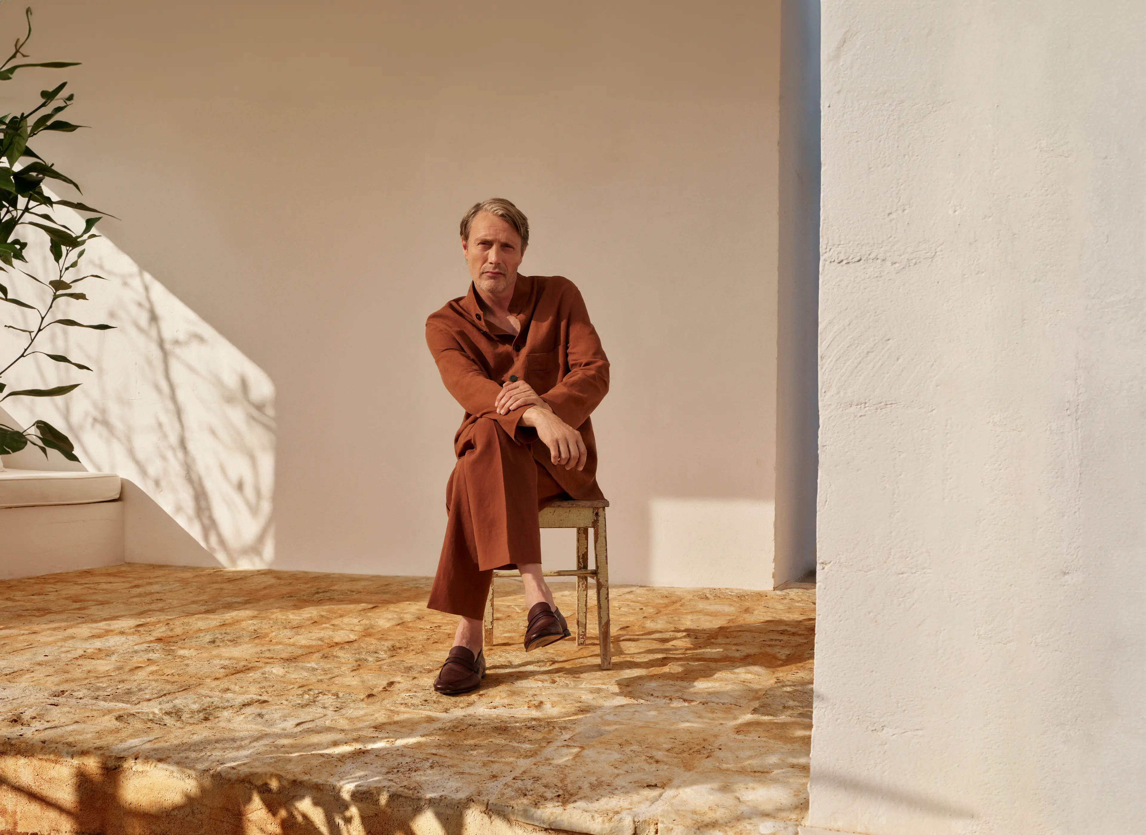 Mads Mikkelsen wearing a refined linen outfit in an earthy tone, paired with leather loafers, from the ZEGNA SS25 collection.