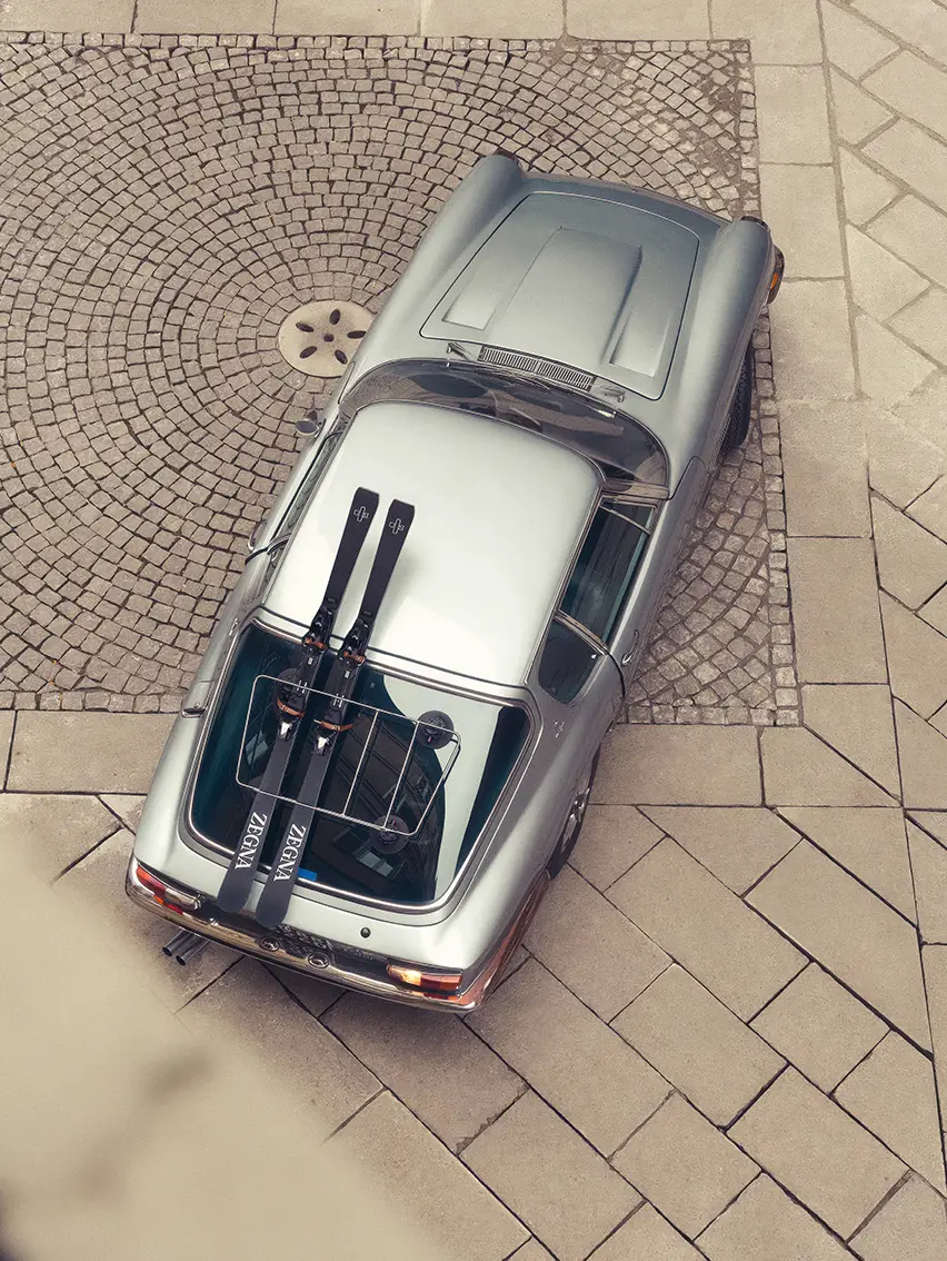 Sports car in a snowy landscape featuring ZEGNA skis, Fall Winter 2025 collection campaign.