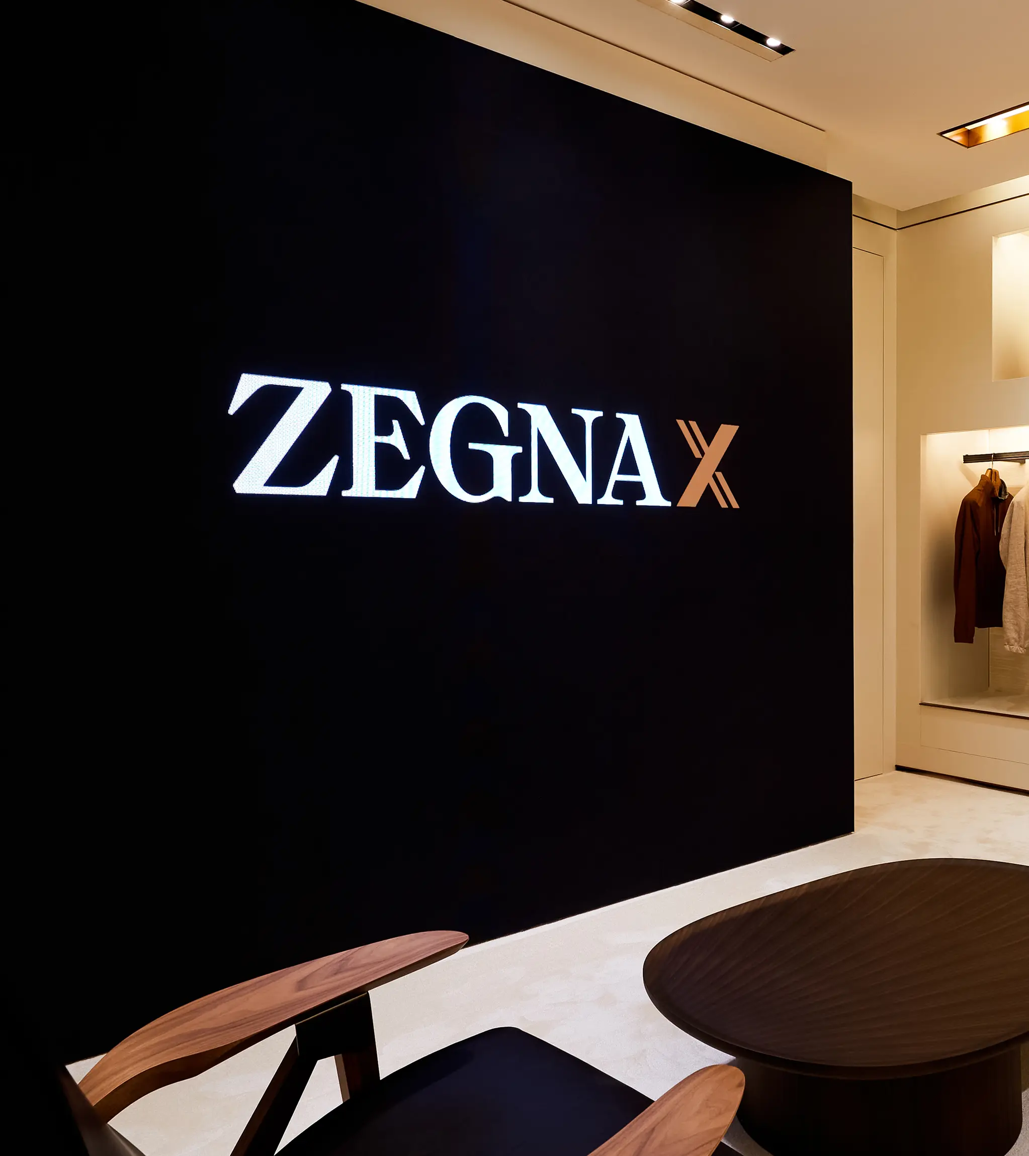 采用 ZEGNA X 徽标墙设计的 ZEGNA（杰尼亚）精品店内景，提供全新 ZEGNA X 衣橱配置服务。